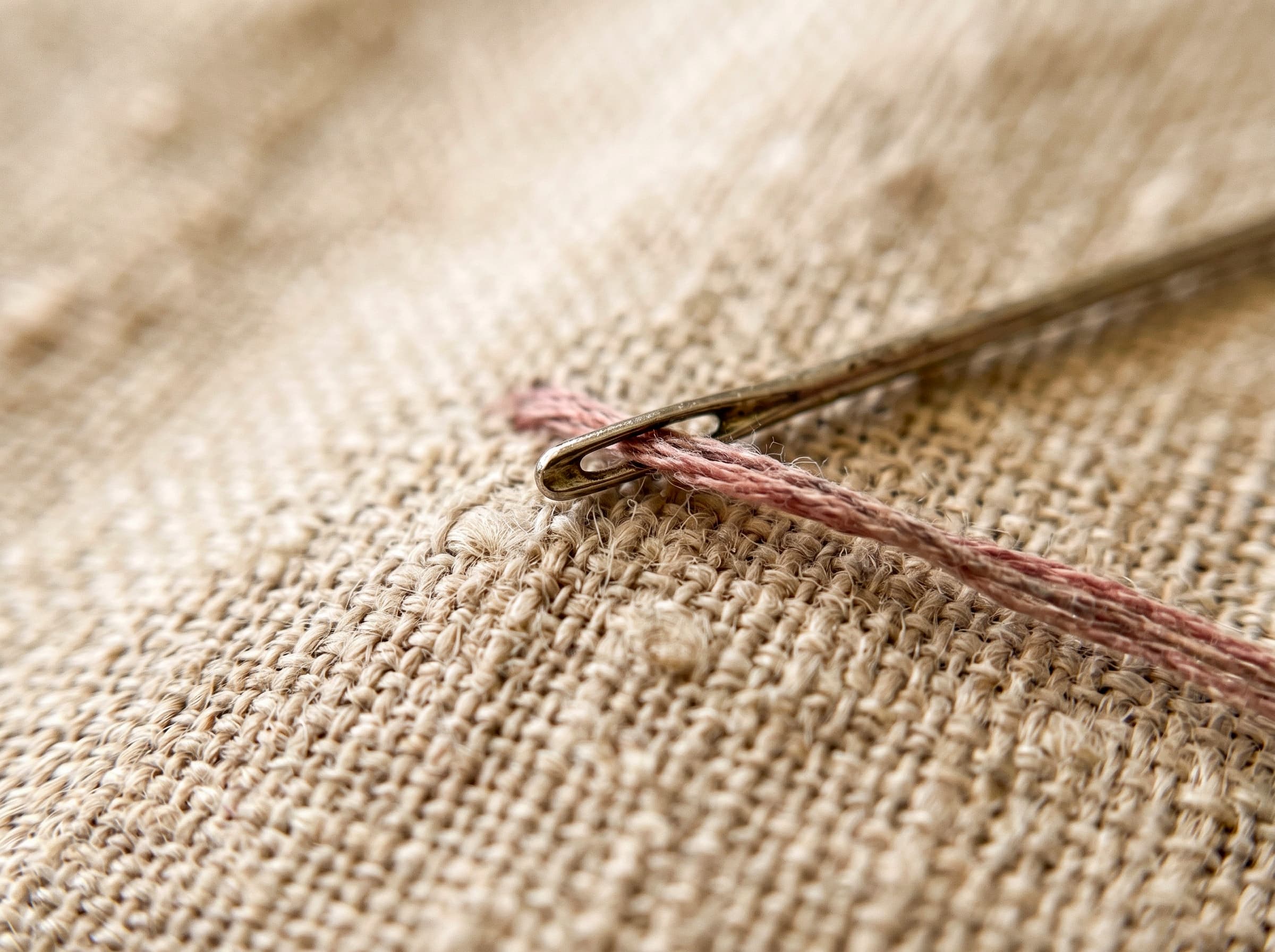 Macro close-up of natural linen fabric showing its irregular, slubby threads.